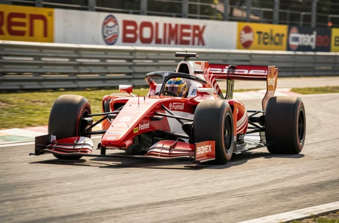 Voiture de course Formula rouge et blanche en plein virage sur un circuit de sport automobile professionnel